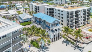 A multi-story hotel with balconies, a pool, and a beach view. - Island Girl vacation Home (Fort Myers Beach)