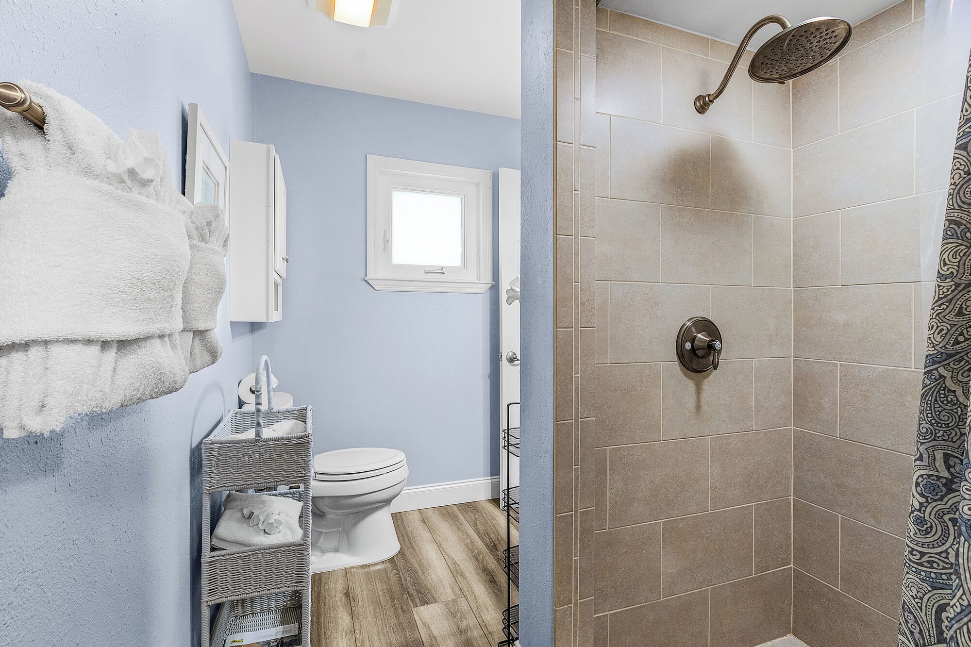 Baño con ducha, inodoro y una cesta de mimbre.