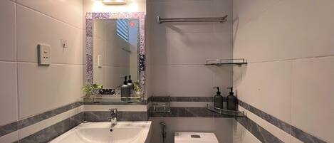 Une salle de bain moderne équipée d’un lavabo, de toilettes et d’une douche.