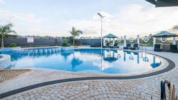A swimming pool with lounge chairs and umbrellas, surrounded by a paved deck. - GL Luxe Suites 2-bedroom apartment in Tatu City (Tatu City)
