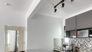 A modern kitchen with a bar area, a microwave, and a tiled backsplash. - GL Luxe Suites 2-bedroom apartment in Tatu City (Tatu City)