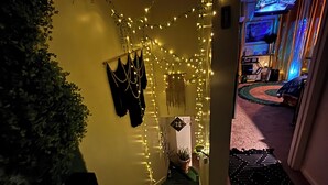 Un couloir décoré de guirlandes lumineuses, un escalier et une pièce comprenant un lit et un téléviseur.