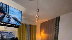 Un salon comprenant une télévision, un tableau, une lampe, un canapé et une table basse.