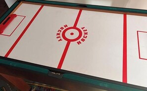 Ein Tischhockey-Spiel mit rotem und weißem Design, mit der Aufschrift 'HOCKEY HOCKEY' um einen zentralen Kreis.