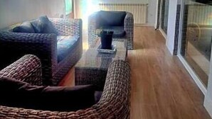 A living room with wicker furniture, a coffee table, and a view of a forest through a window.