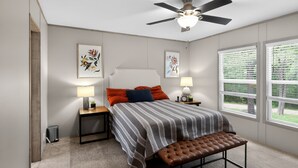 A bedroom with a bed, two bedside tables, a bench, a ceiling fan, and a window with blinds. - Lake Front - Privately Owned Dock with Boat Launch (Quitman)