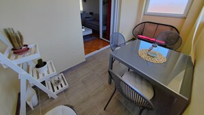A compact living space with a dining area, a sofa, and a window with blinds. - Apartman Roko Pula -blizu centra i plaža, mirna lokacija (Pula)