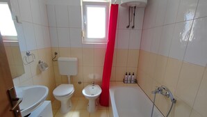 A bathroom with a bathtub, toilet, bidet, and a window. - Apartman Roko Pula -blizu centra i plaža, mirna lokacija (Pula)