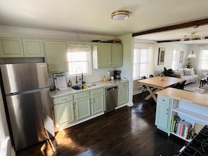Una cocina con un refrigerador de acero inoxidable, un lavamanos y una zona de comedor con mesa y sillas.