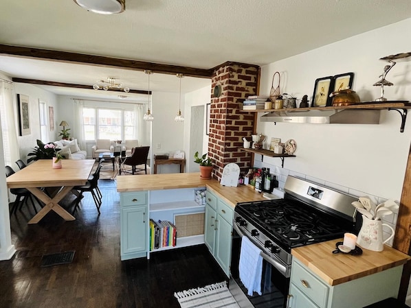 Une cuisine avec une cheminée en briques, une cuisinière à gaz et un coin repas comprenant une table et des chaises.