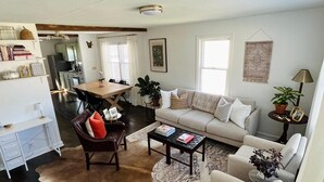 Un salon comprenant un canapé, des fauteuils, une table basse, un tapis et un coin repas avec une table et des chaises.