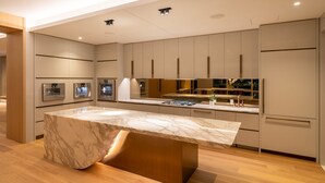 A modern kitchen with built-in appliances, a marble island, and wooden flooring. - Glass Loft Skyline Views + Terrace (Los Angeles)