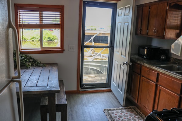 Une cuisine compacte avec des meubles en bois, un four à micro-ondes encastré et une porte-fenêtre coulissante donnant sur un balcon.