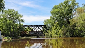 A bridge over a calm river with trees on either side.
