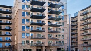 Ein mehrstöckiges Wohnhaus mit Balkonen, Fenstern und einem zentralen Eingang.