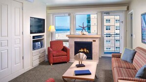 Ein Wohnzimmer mit Kamin, Fernseher, Sofa und Blick auf den Strand.