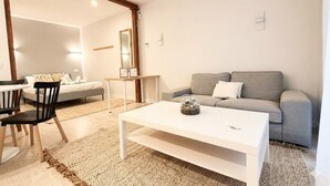 Un salon moderne avec une table basse blanche, un canapé gris et un coin repas comprenant une table et des chaises.