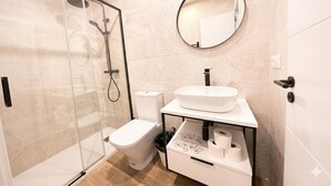 Une salle de bain moderne avec une douche à parois de verre, des toilettes, un lavabo avec un miroir et un porte-rouleau de papier toilette.