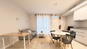 Un salon moderne comprenant un canapé, une table à manger avec des chaises, une table basse et un coin cuisine avec des placards et des appareils électroménagers.