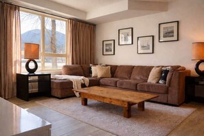 Un salon comprenant un canapé, un pouf, une table basse et des tableaux encadrés accrochés au mur.