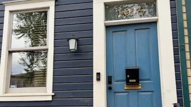 Ein Haus mit blauer Tür, einem Fenster mit weißem Rahmen und einer kleinen Veranda.