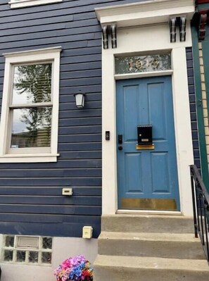 Une maison avec une porte bleue, une fenêtre à cadre blanc et un petit porche.