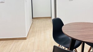 Un pasillo con un cuadro en la pared, un estante pequeño con llaves y una mesa redonda con sillas.
