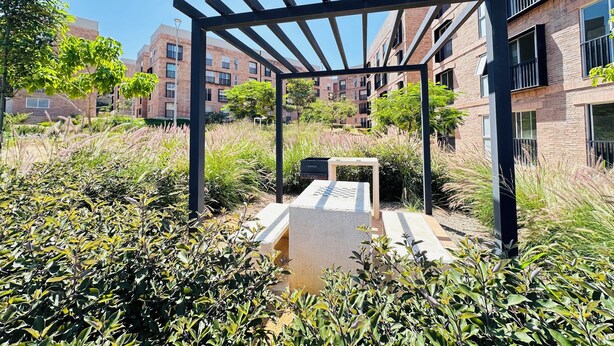 Un patio con una pérgola, una mesa de ajedrez y abundante follaje.