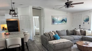 A modern living room with a gray sectional sofa, a coffee table, and a bar area with stools. - Weeki Wachee 3BR Private Dock, Kayak, Fish & Boat, Trailer Parking, Sleeps 6 (Spring Hill)