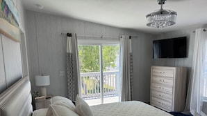A bedroom with a large bed, a dresser, a television, and a balcony. - Weeki Wachee 3BR Private Dock, Kayak, Fish & Boat, Trailer Parking, Sleeps 6 (Spring Hill)