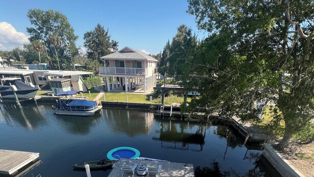 A calm water body with docks, a floating platform, and a house in the background. - Weeki Wachee 3BR Private Dock, Kayak, Fish & Boat, Trailer Parking, Sleeps 6 (Spring Hill)