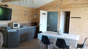 Una cocina moderna con microondas, pileta y muebles de madera. Hay una zona de comedor con una mesa y sillas.