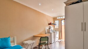 Ein Schlafzimmer mit Bett, Schreibtisch, Stuhl, Kleiderschrank und einer Küchenzeile.