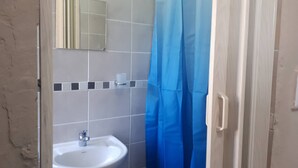 Ein Badezimmer mit einem weißen Waschbecken, einem Spiegel und einem blauen Duschvorhang.