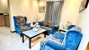 Uma sala de estar com dois poltronas azuis, uma mesa de centro e um sofá.
