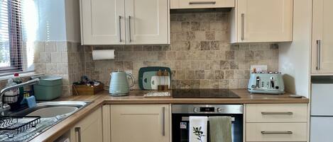 A compact kitchen with a dishwasher, a kettle, a toaster, and a sink.
