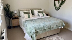 Um quarto com cama, mesa de cabeceira, abajur e uma planta em vaso.