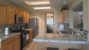 A kitchen with wooden cabinets, a stainless steel refrigerator, a microwave, and a stove. - Hook, Line & Relax – Coastal TX Getaway (Texas City)