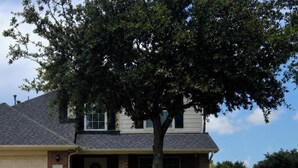 A residential house with a garage, a lawn, and a tree in front. - Hook, Line & Relax – Coastal TX Getaway (Texas City)