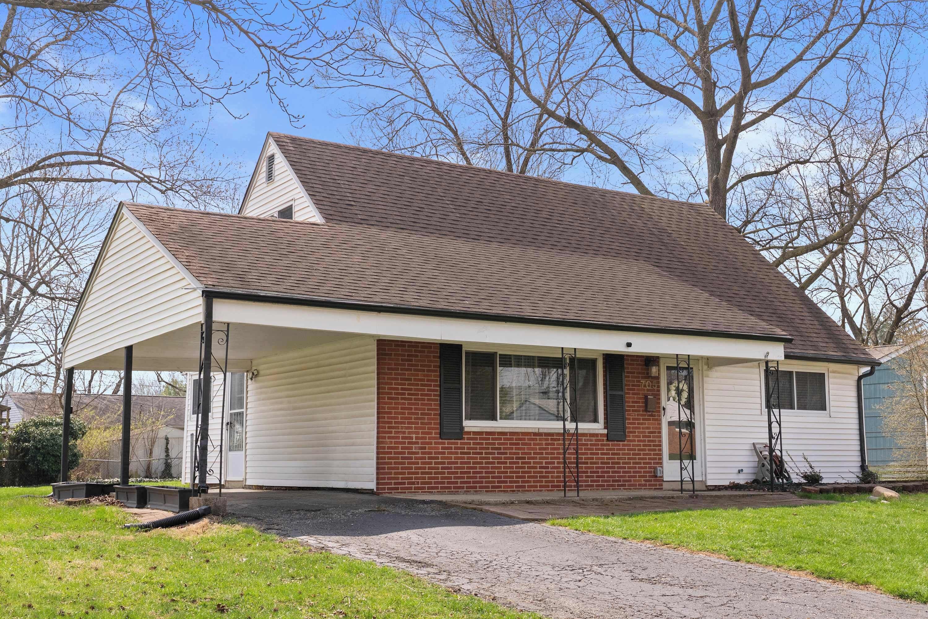 A single-story house with a covered porch, a brick exterior, and a garage door.
