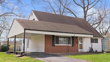 A single-story house with a covered porch, a brick exterior, and a garage door.