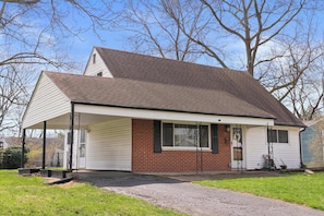 A single-story house with a covered porch, a brick exterior, and a garage door. - OSU + Downtown Spacious 4BR Sleeps 8 (Columbus)