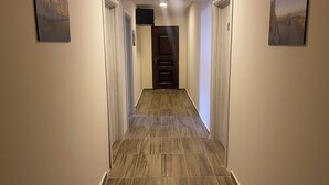 A hallway with wooden flooring, white walls, and doors leading to rooms. - City Suites Budva  (Budva)