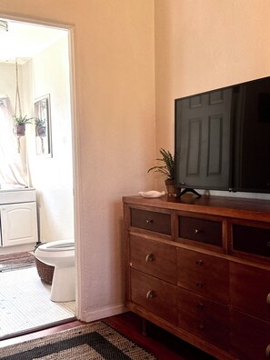 A room with a wooden dresser, a television, and a door leading to another room. - SUNNY SANTA MONICA GARDEN DUPLEX W ALLEYWAY ENTRANCE + PATIO (Santa Monica)