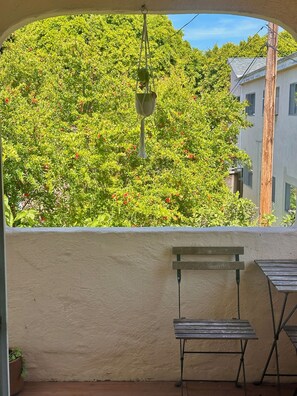 A balcony with a hanging planter, a wooden bench, and a view of a lush green hillside. - SUNNY SANTA MONICA GARDEN DUPLEX W ALLEYWAY ENTRANCE + PATIO (Santa Monica)