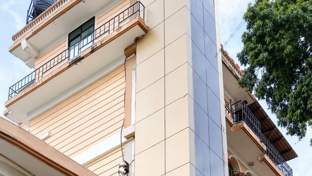 Un edificio de varios pisos con balcones, unidades de aire acondicionado y una escalera decorada con plantas en macetas.