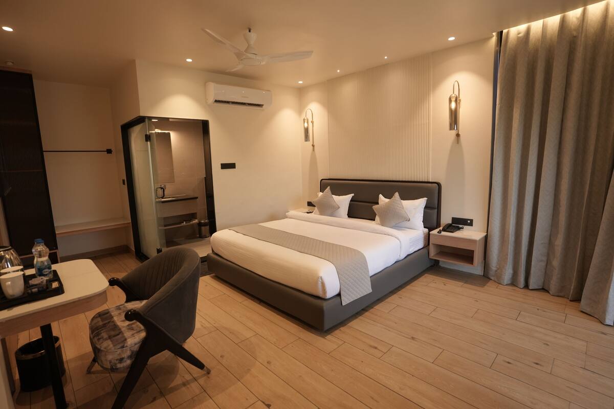 A modern hotel room with a large bed, bedside tables, a desk, a chair, and a ceiling fan.