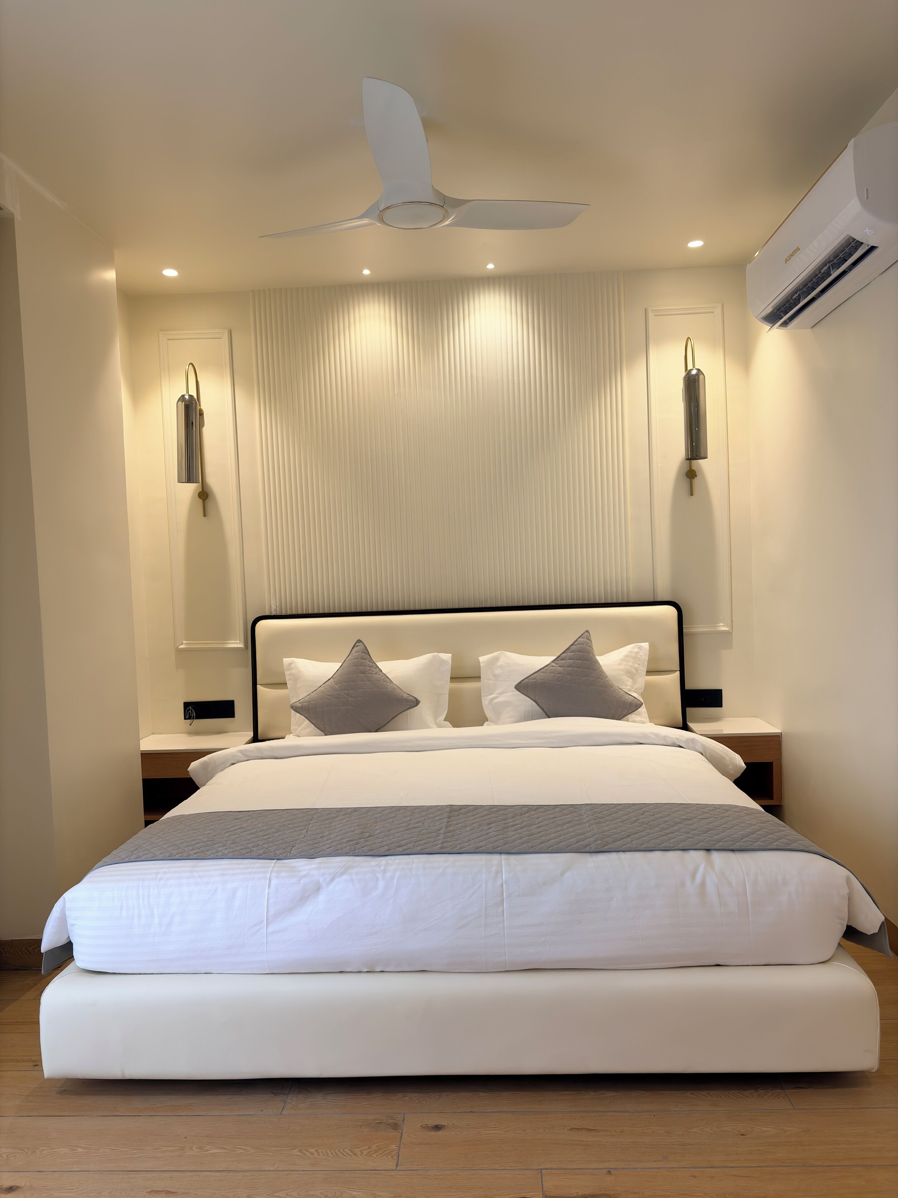Ein modernes Schlafzimmer mit einem großen Bett, einem Deckenventilator, Einbautenleuchten und einer Klimaanlage.