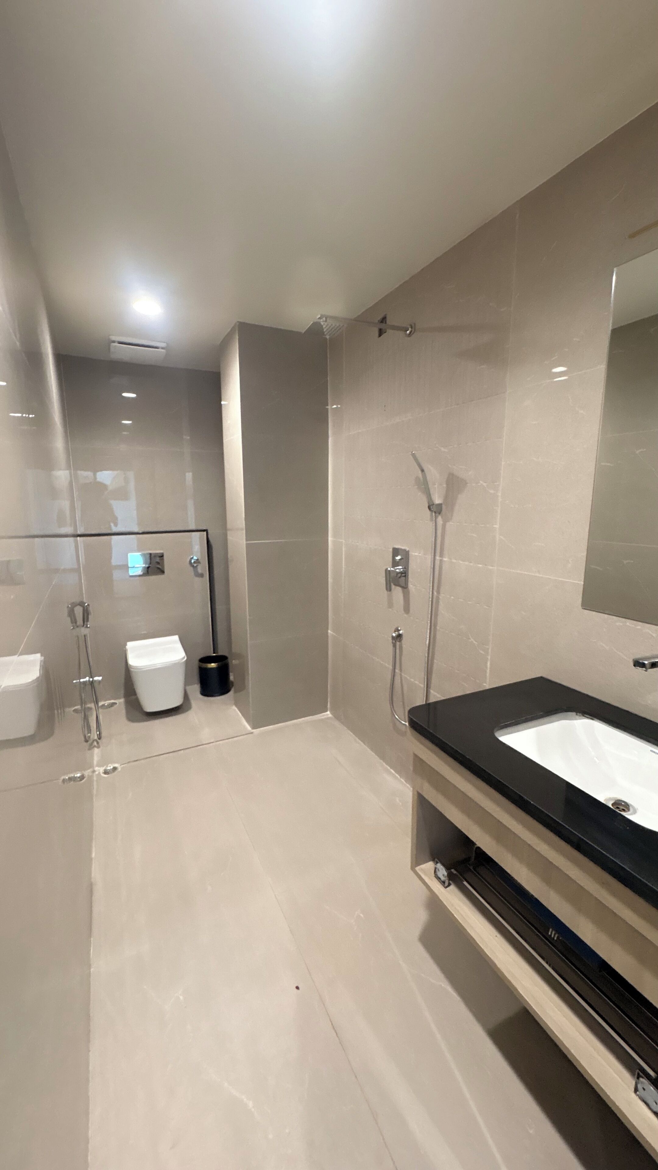 A modern bathroom with a glass-enclosed shower, a toilet, and a sink with a mirror.