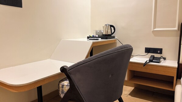 Una habitación pequeña y moderna, con escritorio, silla y cafetera.